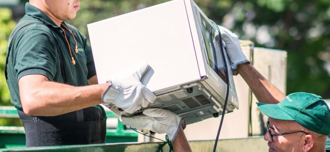 descrição: dois funcionários da Ecoassist segurando um microondas. Zurich Seguros e Ecoassist - Descarte Ecológico como benefício para o segurado e coleta de Salvados em Garantia Estendida